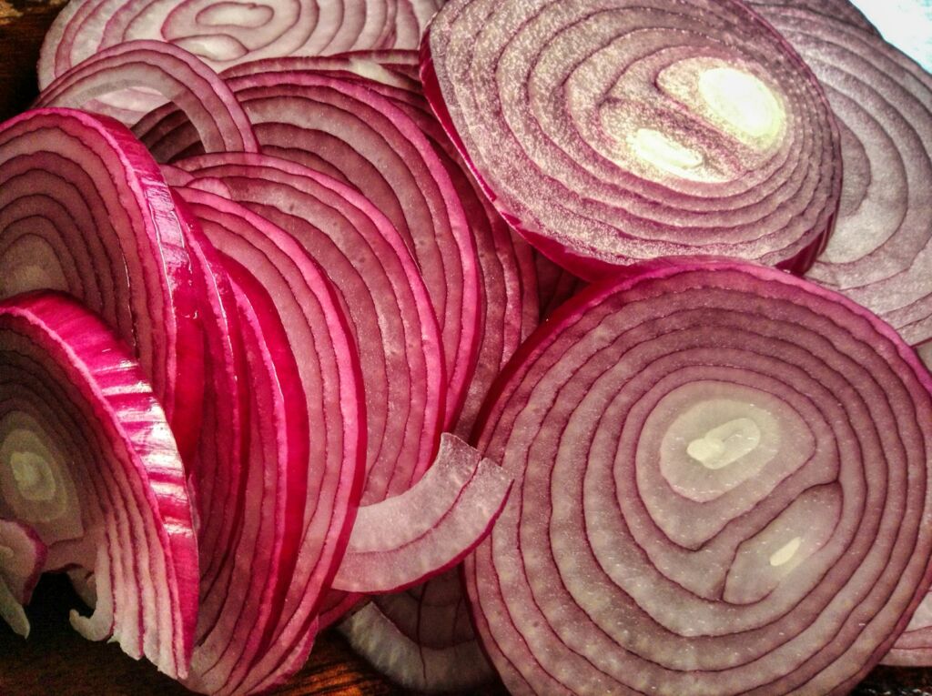 A pile of red onions sitting on top of a table